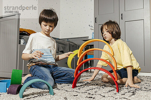 Boys building pyramid with colorful rainbow toys at home