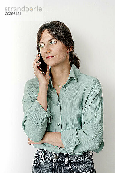 Woman talking on smart phone in front of wall