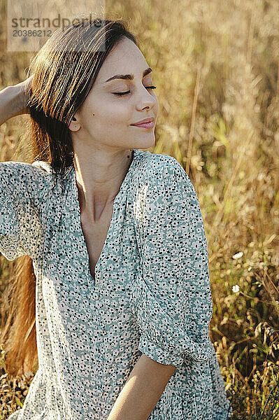 Beautiful woman sitting with eyes closed in meadow