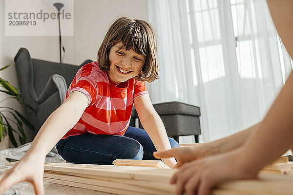 Smiling girl and brother with planks in living room