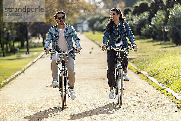 Happy couple cycling and having fun on footpath at park