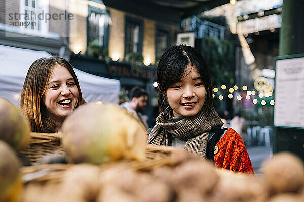 Smiling sisters looking at vegetables in market