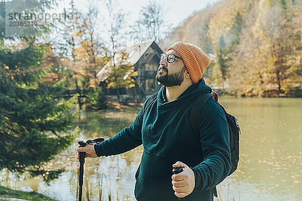 Hiker hiking with walking poles by lake in forest