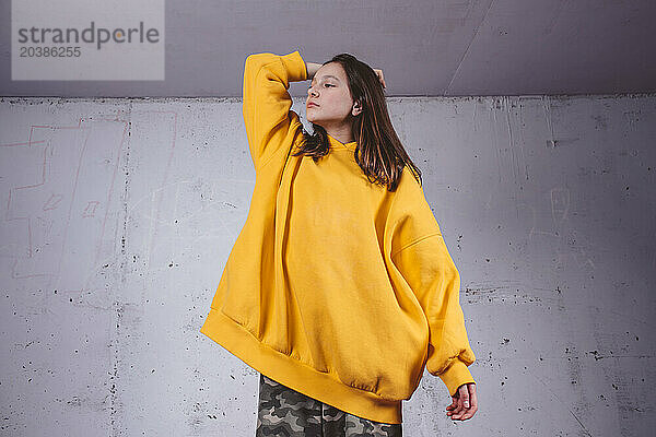 Girl in yellow hoodie posing on gray background