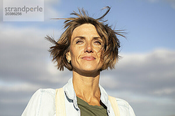 Smiling woman with short hair under sky