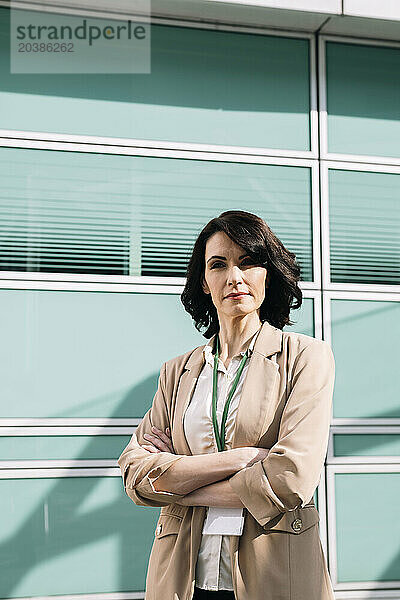 Confident mature businesswoman wearing blazer standing with arms crossed