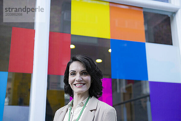 Smiling beautiful mature businesswoman in front of colorful window