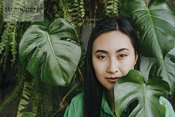 Young woman near monstera leaves