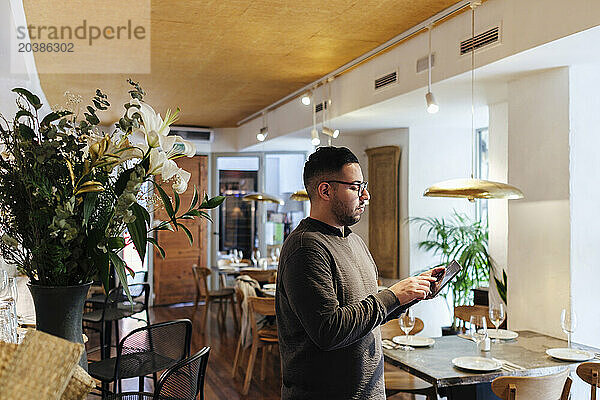 Restaurant owner wearing eyeglasses using tablet PC