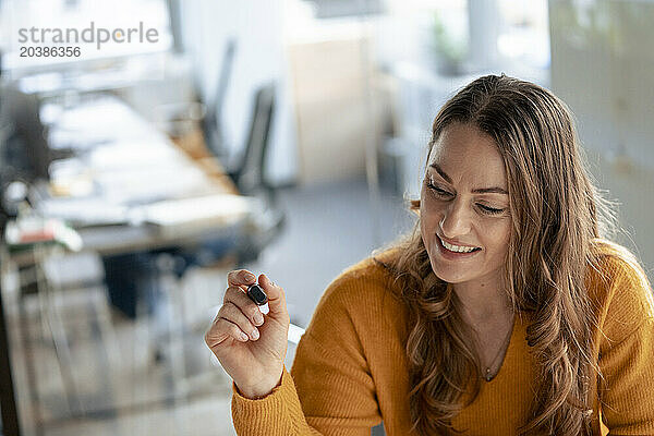 Happy businesswoman with felt tip pen in office