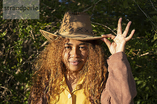 Young woman with curly hair wearing cowboy hat