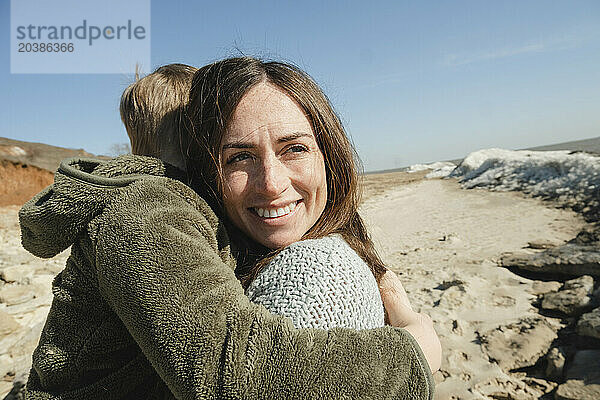 Happy mother and son embracing each other on sunny day