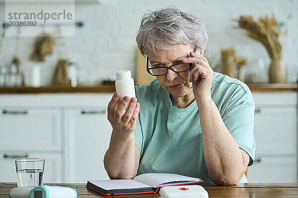 Senior woman analyzing medicine bottle at home