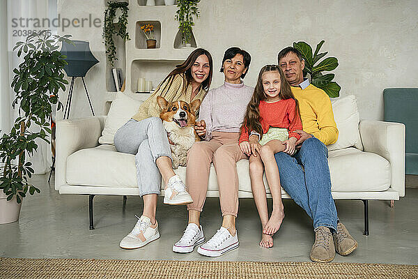 Happy family sitting with dog on sofa at home