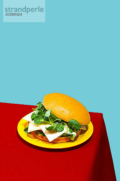 Chicken burger with cheese and lettuce on table against blue background