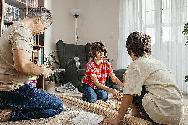 Father and children assembling furniture in living room