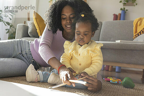 Young mother and daughter painting together in living room