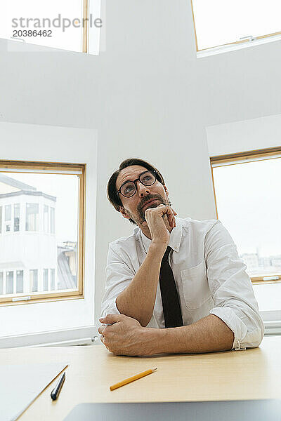 Thoughtful businessman sitting at desk in office