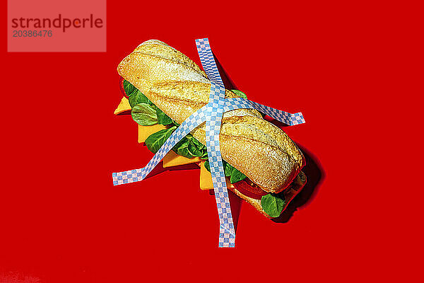 Cheese sandwich sticked on red background using adhesive tape