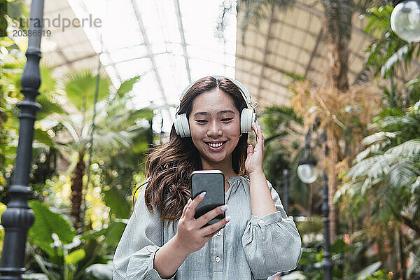 Smiling young woman listening to music through wireless headphones