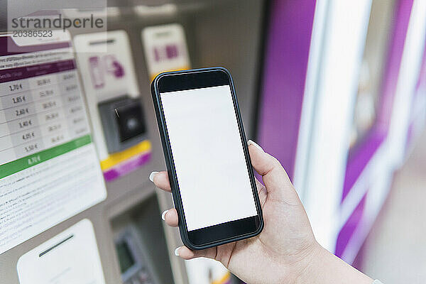 Hand of woman using mobile app at ticket vending machine