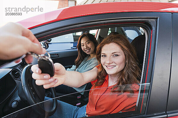 Smiling woman taking car key from salesman