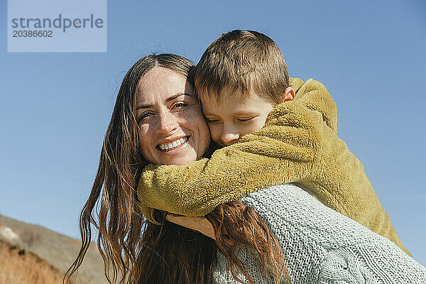 Son with arm around mother under clear sky