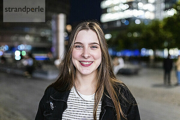 Happy beautiful young woman in city at night