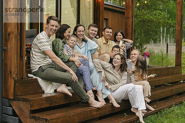 Cheerful family and friends sitting together on steps of house