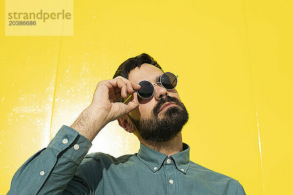 Man wearing sunglasses in front of yellow wall