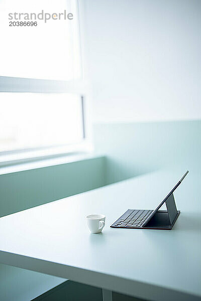 Tablet PC with keyboard kept near coffee cup on desk