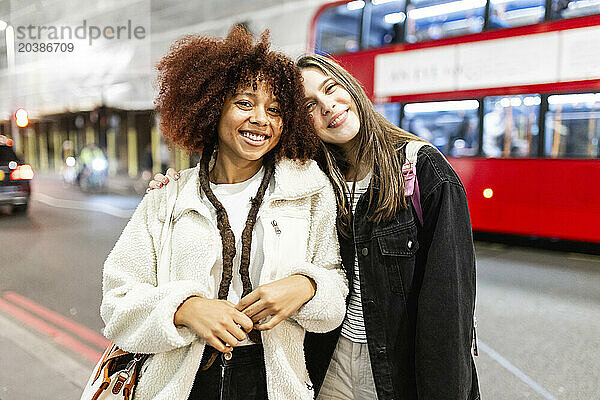 Happy young women standing together on street in city at night