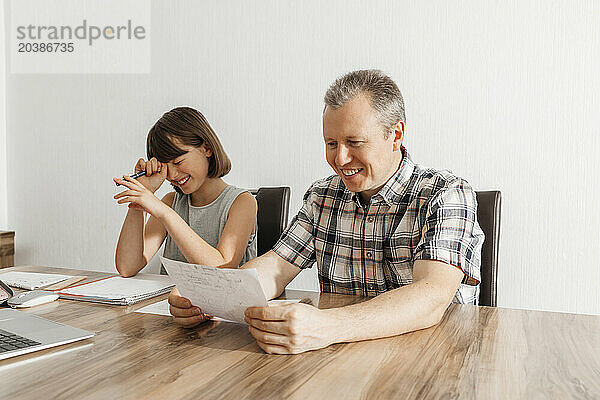 Happy father reading daughter's homework at home