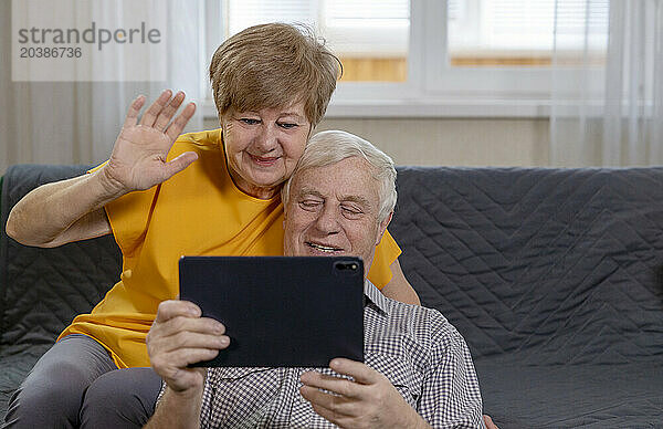 Senior couple talking via video call on tablet PC at home