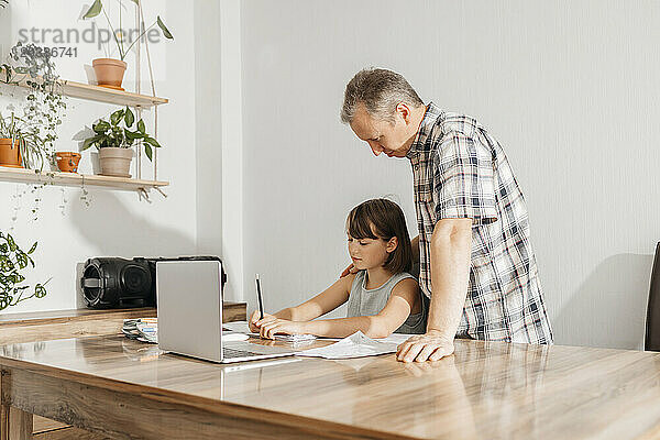 Father helping daughter studying at home