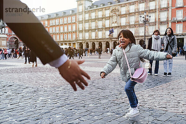 Cheerful girl running towards father at town square