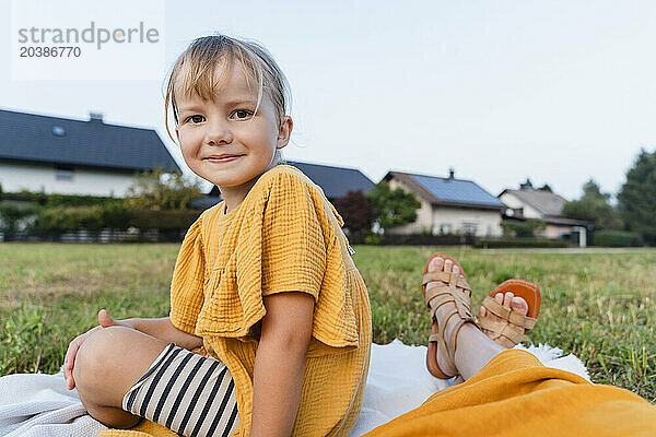 Smiling girl sitting with mother in meadow