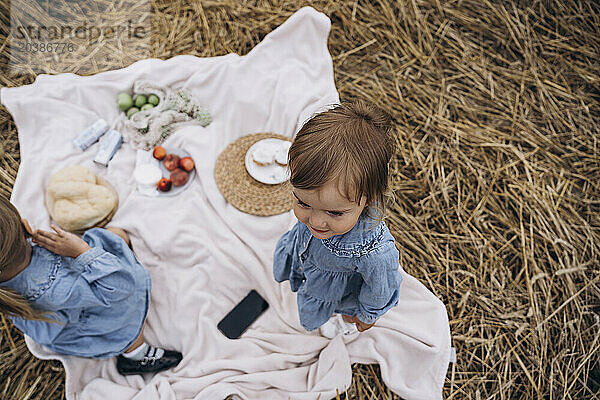 Sisters in denim dresses on picnic blanket