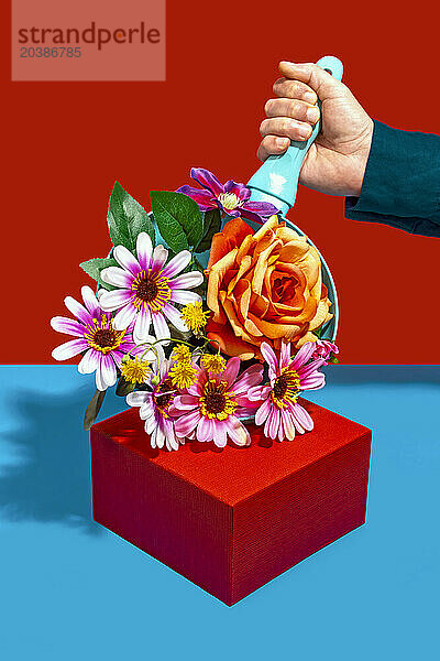 Man holding frying pan with colorful flowers near red box