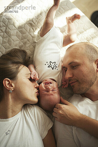Parent lying on bed with baby boy at home