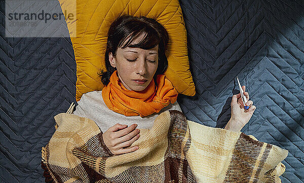 Sick woman with thermometer sleeping on bed at home