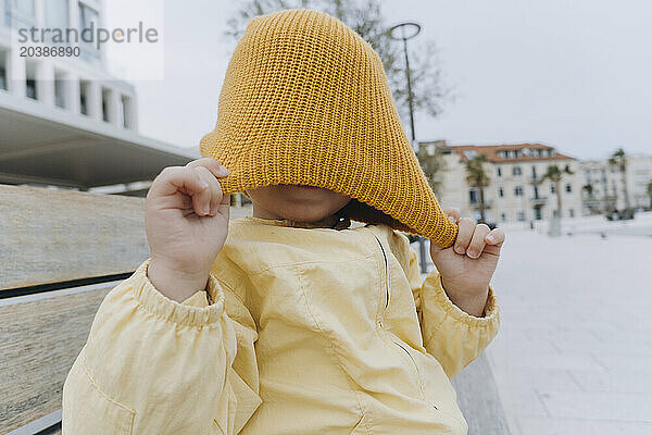 Boy playing with orange knit hat