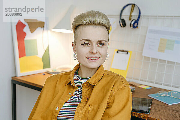 Smiling young woman sitting near desk at home