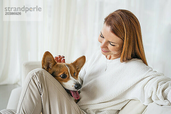 Smiling woman sitting with dog in living room