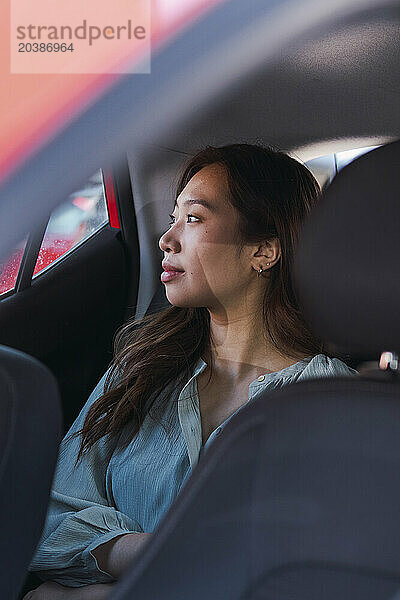 Young woman looking out of window sitting in car