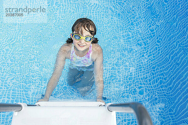 Smiling girl wearing swimming goggles in pool