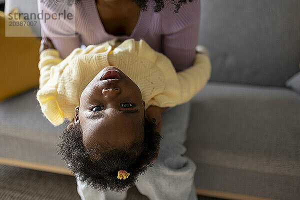 Young mother playing with daughter in living room at home