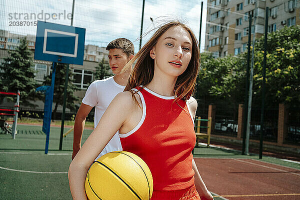 Basketball player walking with friend in background at school yard