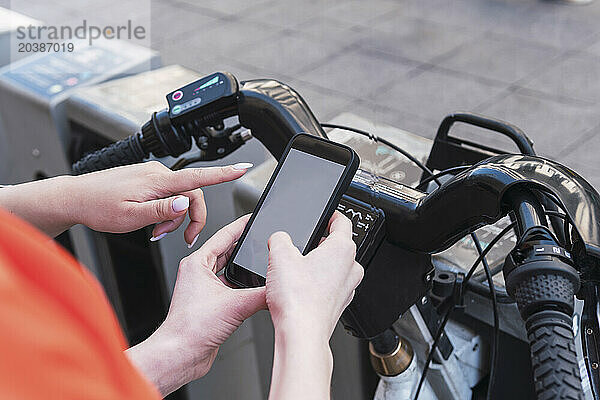 Friends scanning bar code to rent electric cycle in city