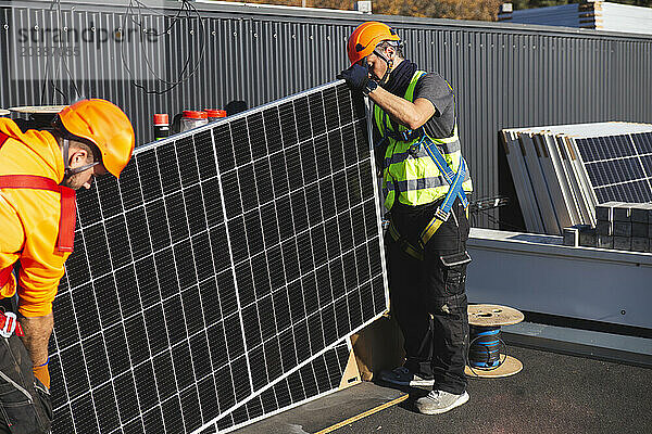 Coworkers with solar panel installing on rooftop